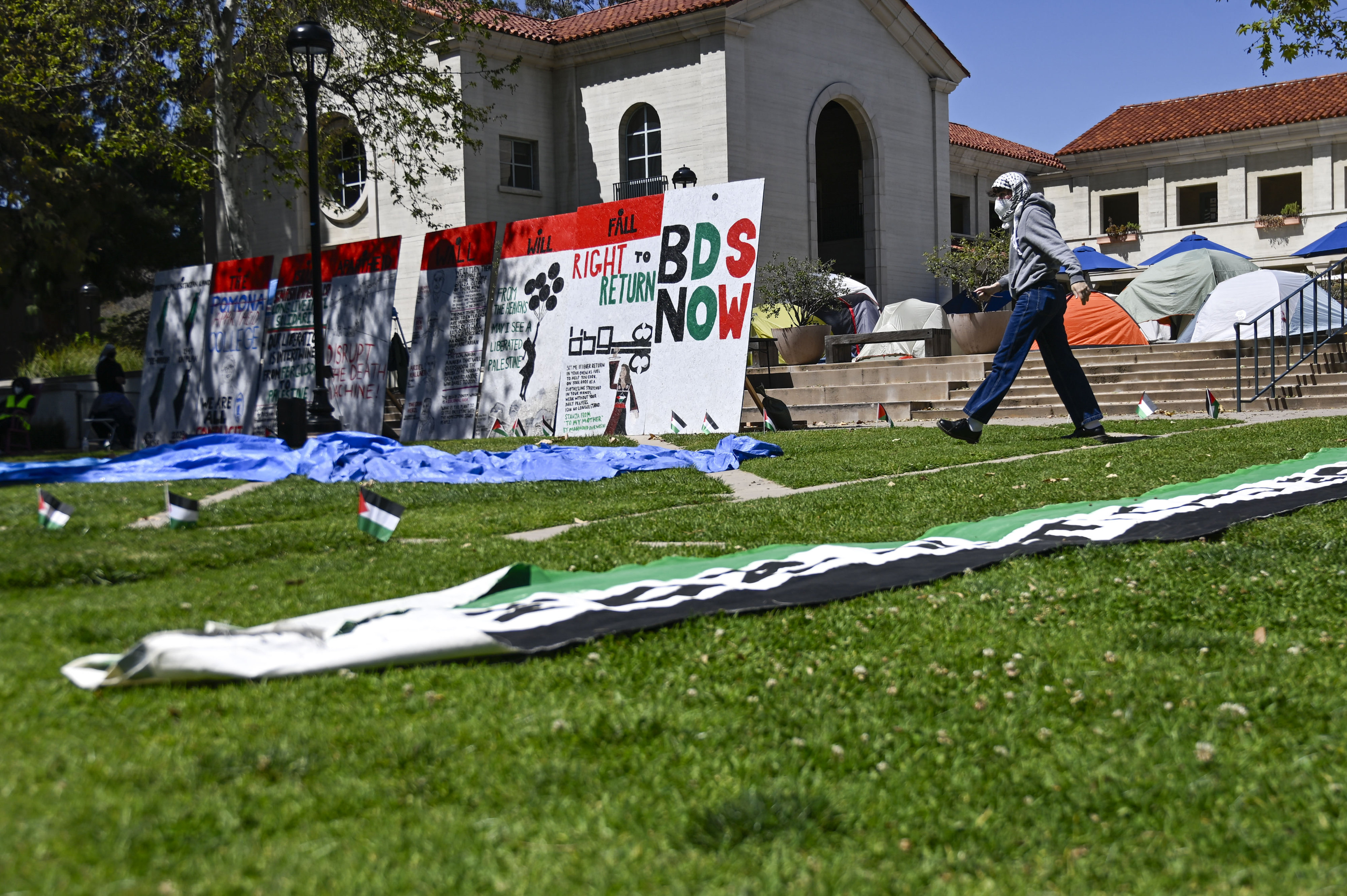 A student protester at Pomona College walks near the mock...
