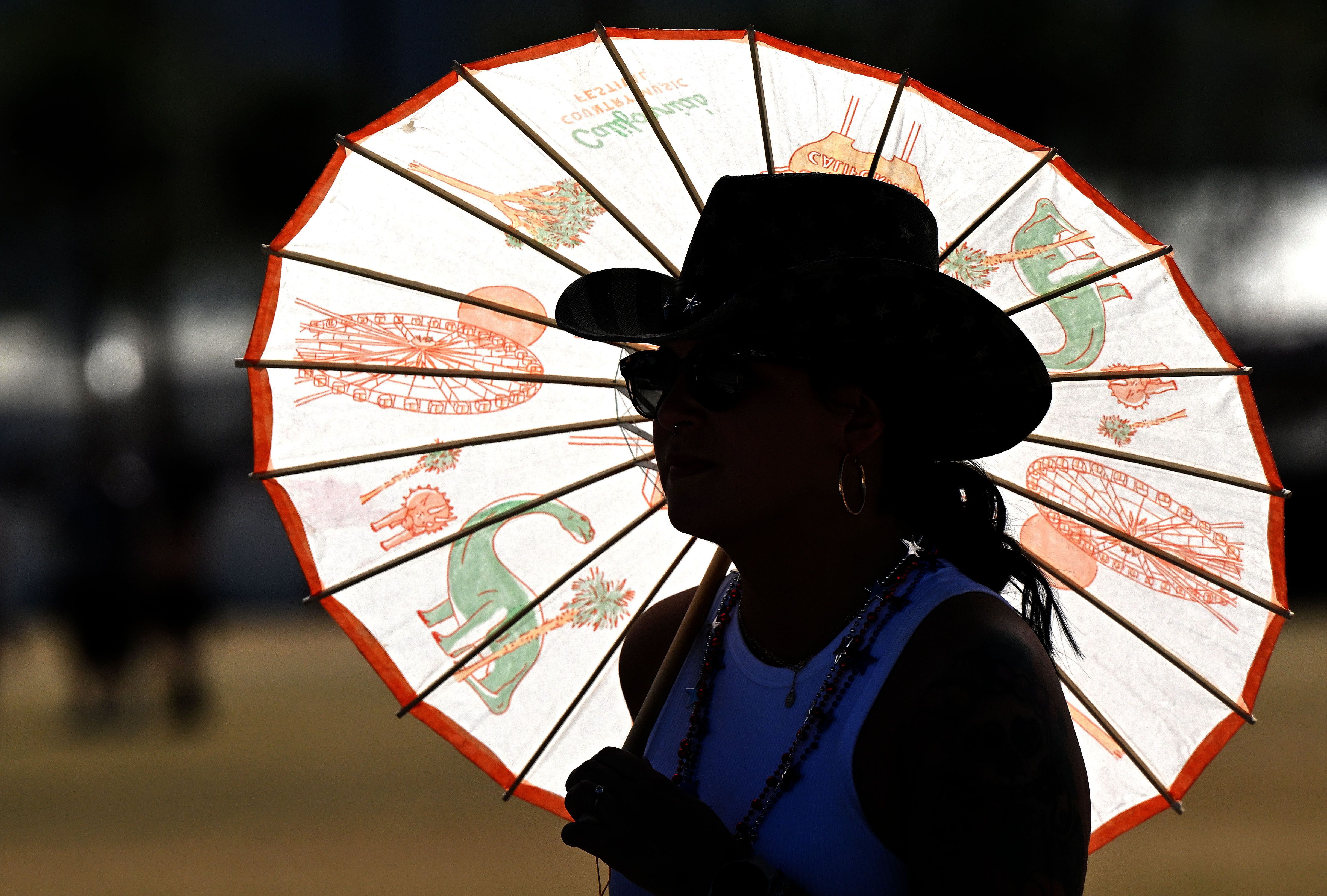 A country music fan uses an umbrella for shade on...